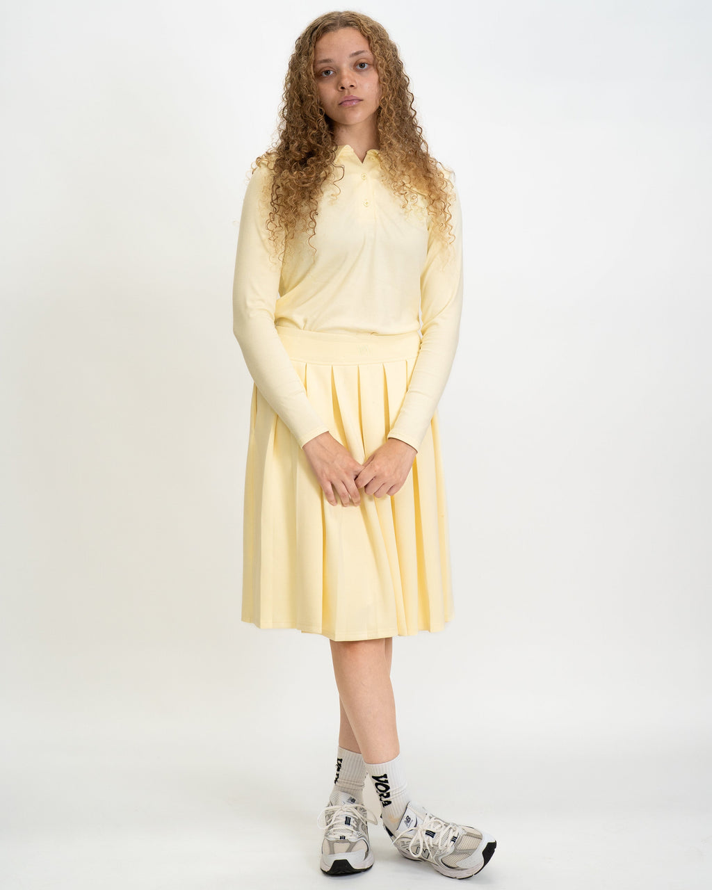 Woman wearing a light yellow dress and shoes on a white background