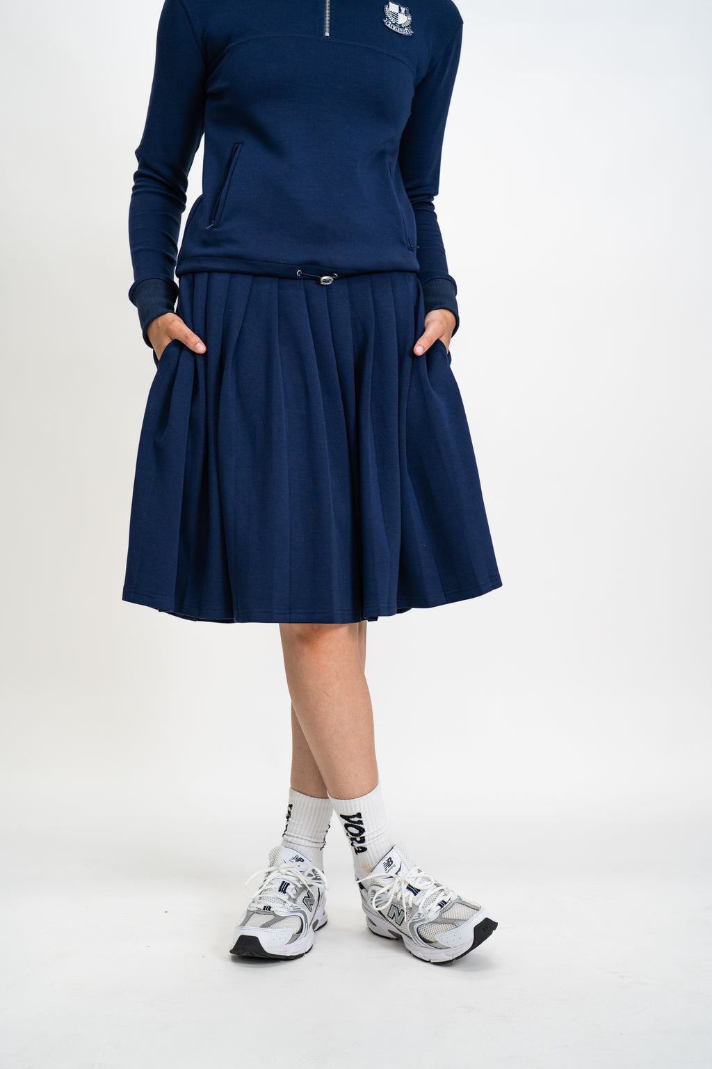 Person wearing a navy blue outfit with a skirt on a white background