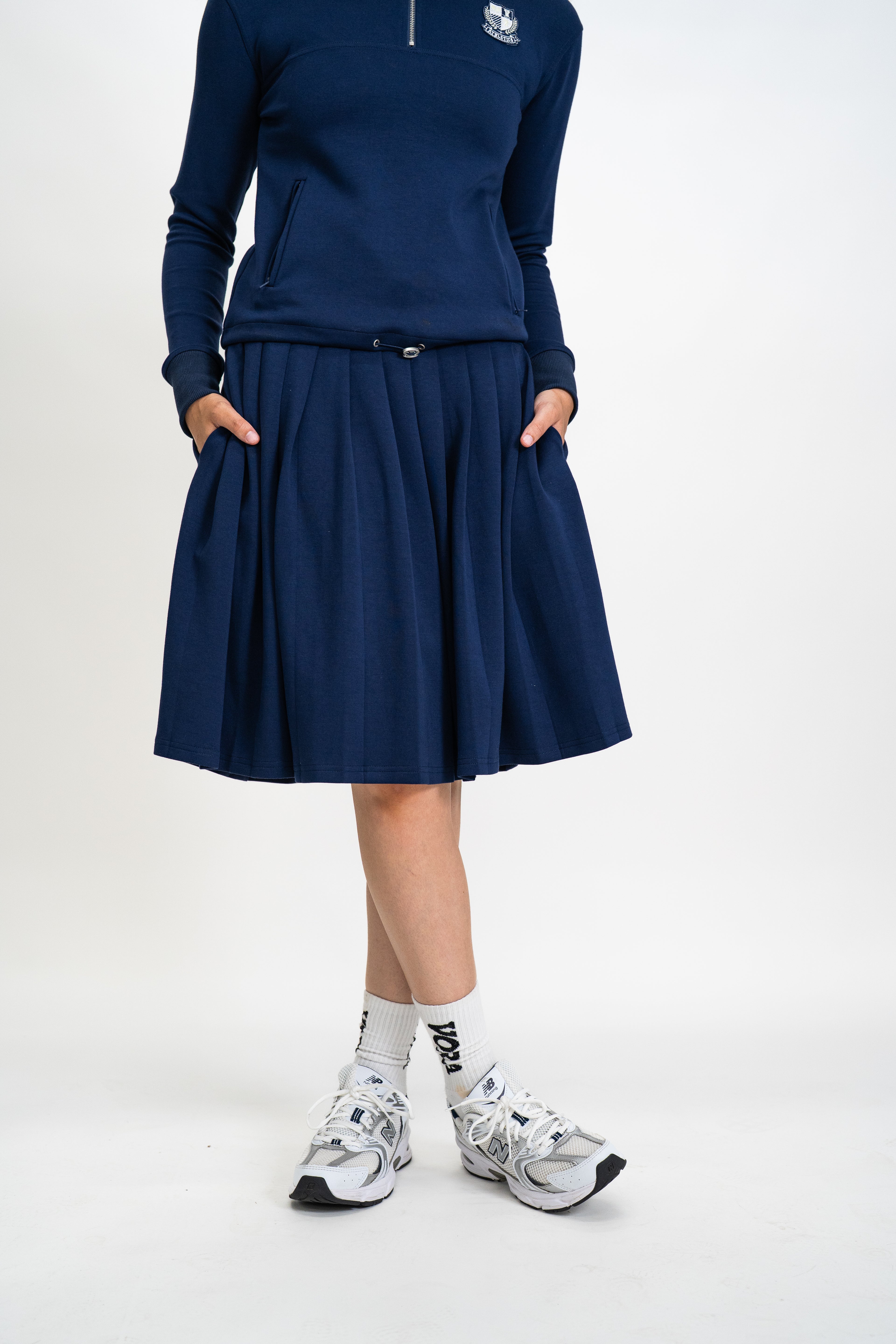 Person wearing a navy blue outfit with a skirt on a white background
