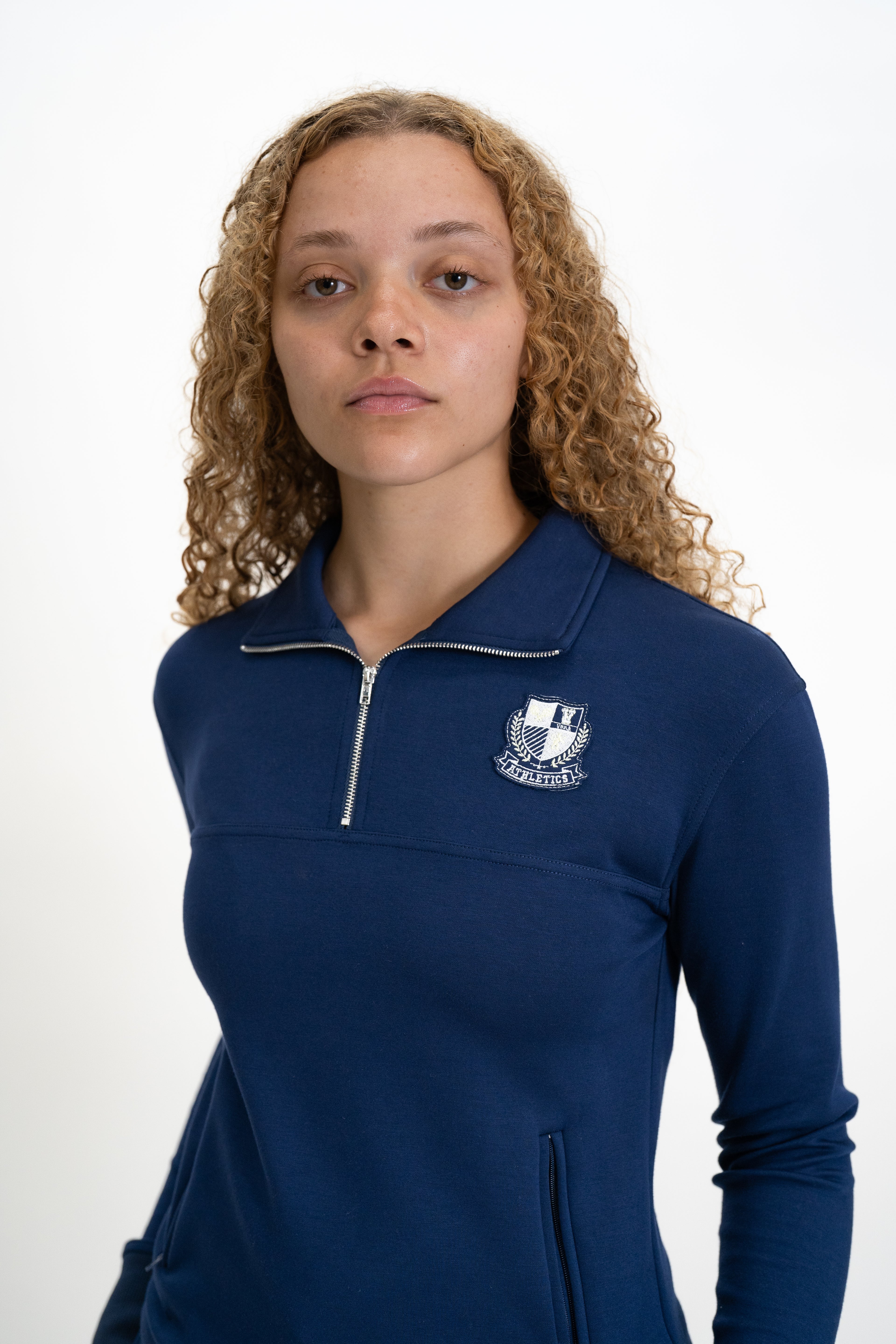 Person wearing a navy blue pullover with a logo on a white background