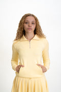 Woman wearing a yellow long-sleeve top with a zipper on a white background