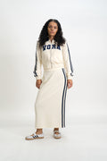 Person wearing a cream-colored tracksuit with 'VORA' text on a white background